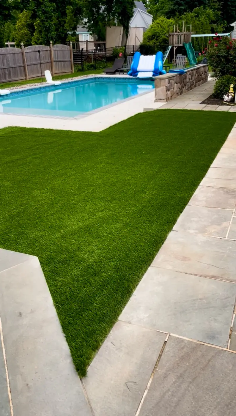 Turf lawn and bluestone paving beside a pool by Mex Landscaping