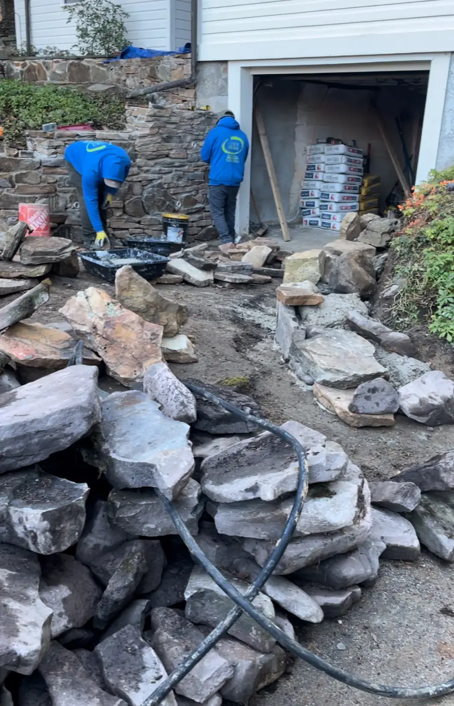 Mex Landscaping masons hand-laying a natural fieldstone retaining wall